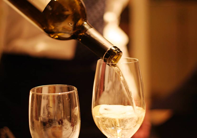 Waiter pouring a glass of white wine.